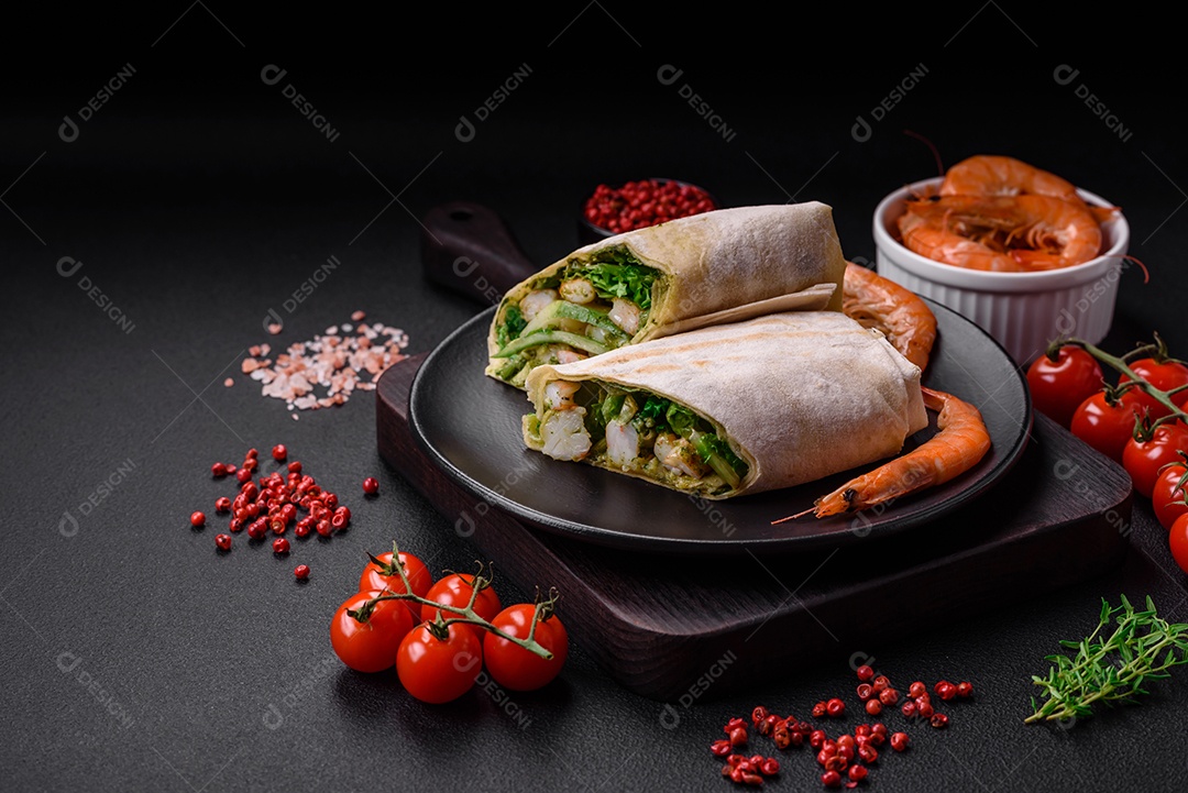 Delicioso pão fresco com camarões, tomates, alface e pepino em pão pita sobre um fundo escuro de concreto