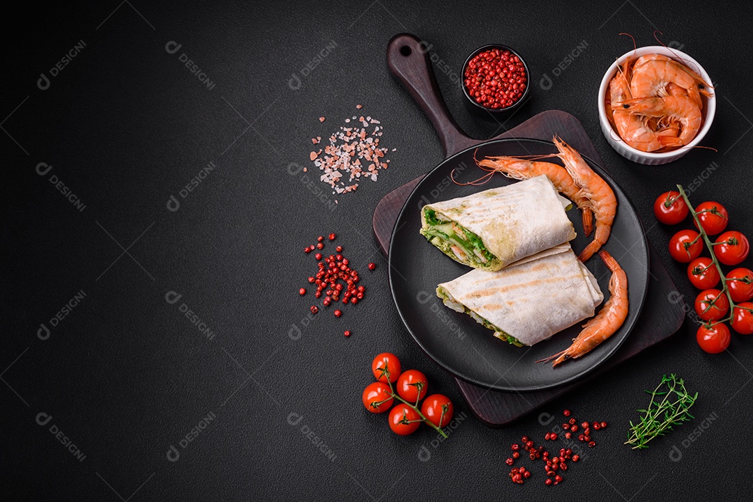 Delicioso pão fresco com camarões, tomates, alface e pepino em pão pita sobre um fundo escuro de concreto