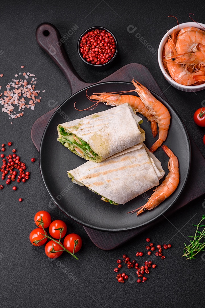 Delicioso pão fresco com camarões, tomates, alface e pepino em pão pita sobre um fundo escuro de concreto