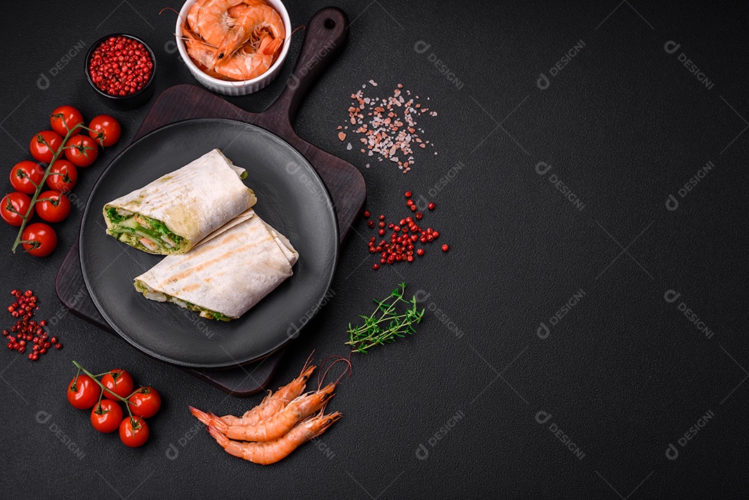 Delicioso pão fresco com camarões, tomates, alface e pepino em pão pita sobre um fundo escuro de concreto