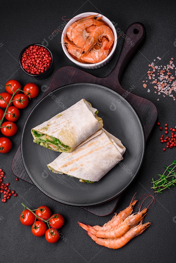 Delicioso pão fresco com camarões, tomates, alface e pepino em pão pita sobre um fundo escuro de concreto