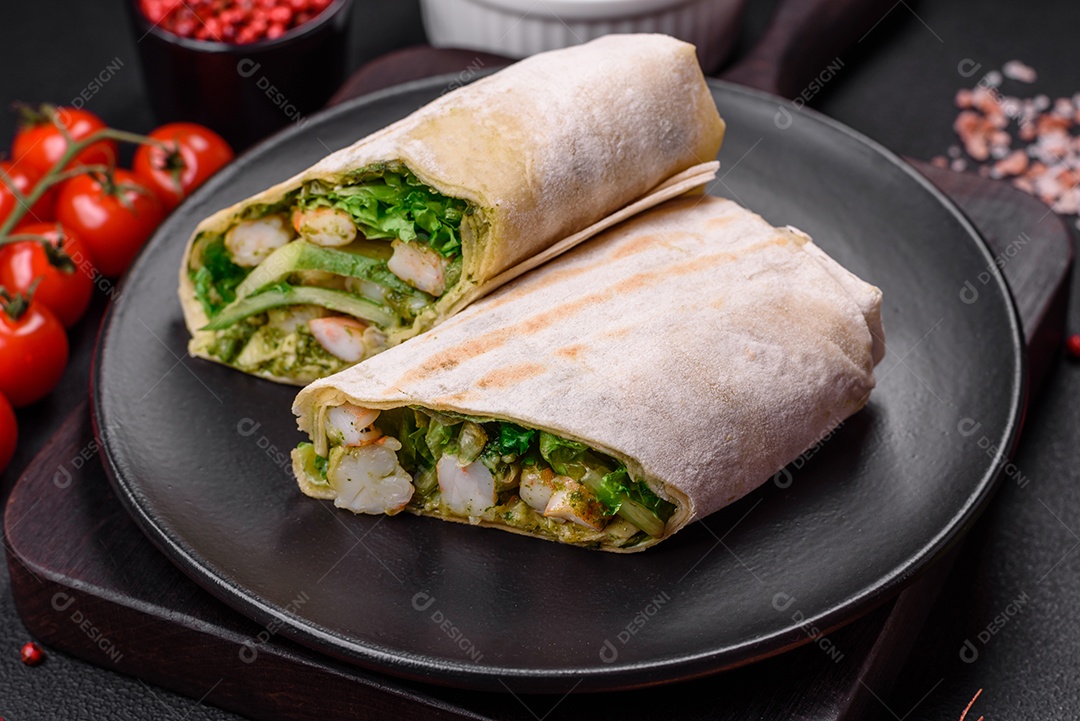 Delicioso pão fresco com camarões, tomates, alface e pepino em pão pita sobre um fundo escuro de concreto