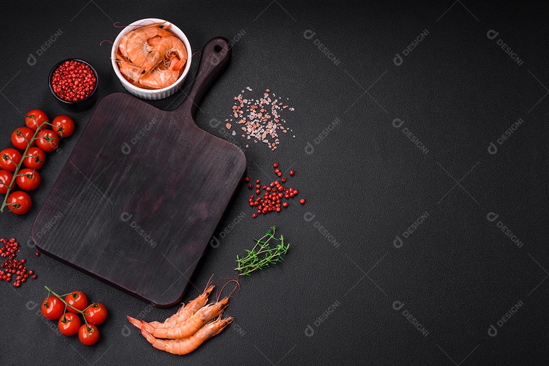 Ingredientes para cozinhar tomate cereja, camarão, sal e especiarias com lugar para inscrição em fundo escuro de concreto