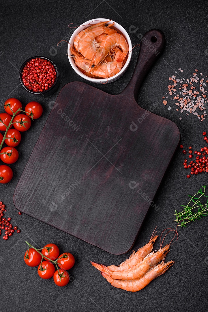 Ingredientes para cozinhar tomate cereja, camarão, sal e especiarias com lugar para inscrição em fundo escuro de concreto