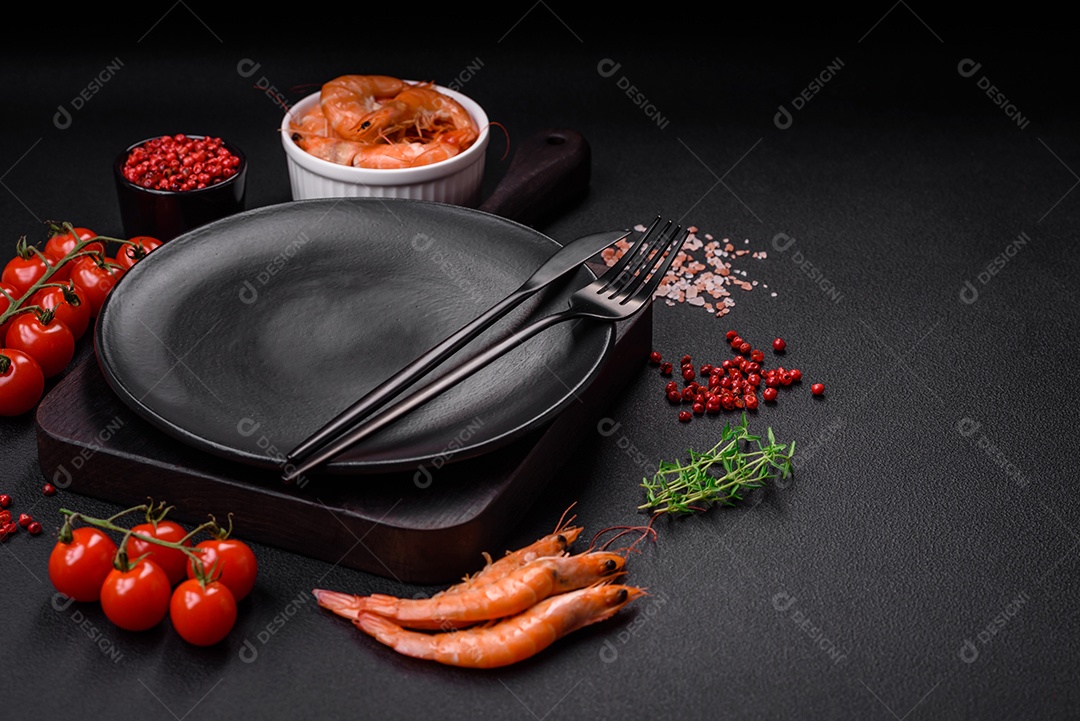 Ingredientes para cozinhar tomate cereja, camarão, sal e especiarias com lugar para inscrição em fundo escuro de concreto