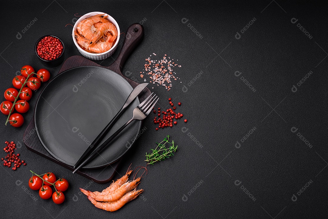 Ingredientes para cozinhar tomate cereja, camarão, sal e especiarias com lugar para inscrição em fundo escuro de concreto
