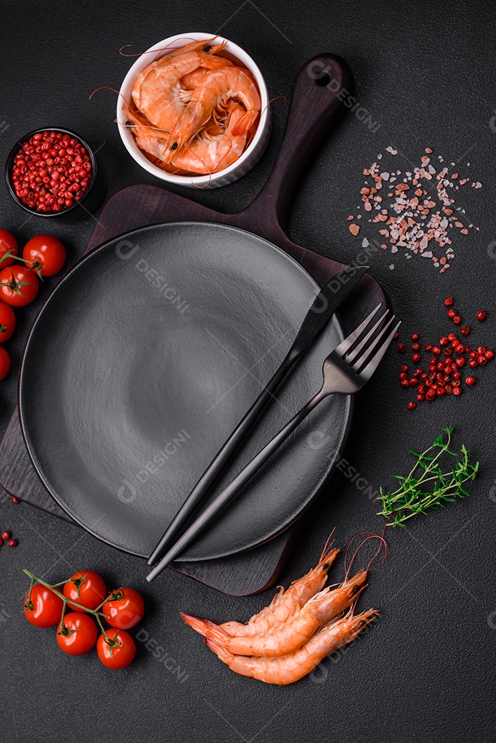 Ingredientes para cozinhar tomate cereja, camarão, sal e especiarias com lugar para inscrição em fundo escuro de concreto