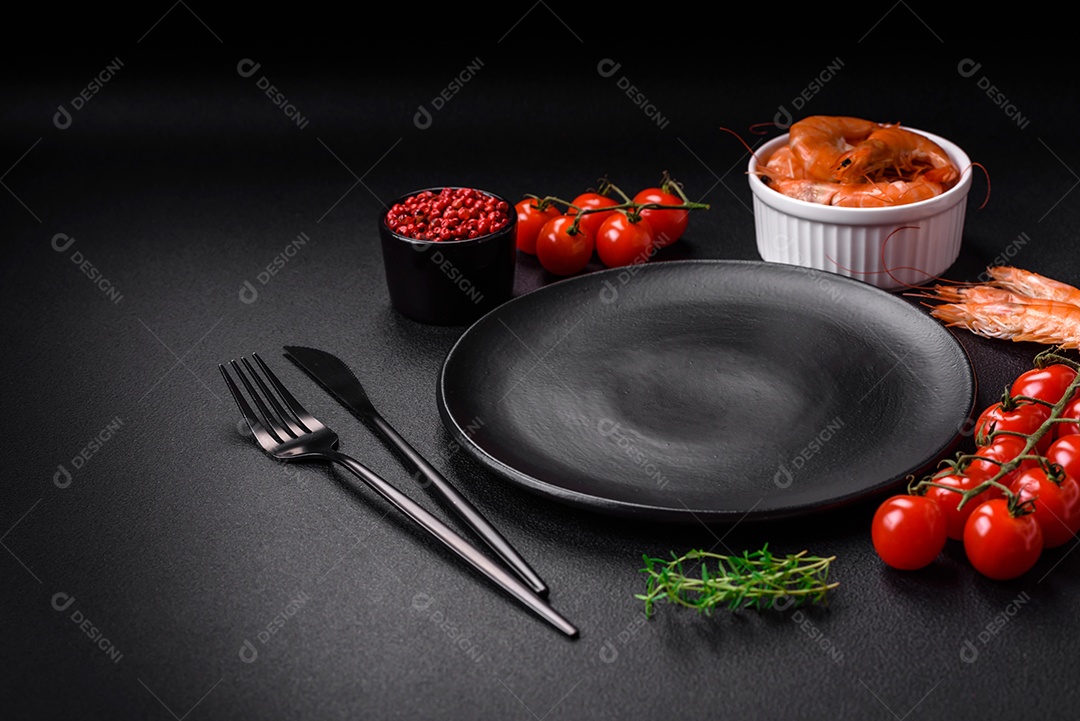 Ingredientes para cozinhar tomate cereja, camarão, sal e especiarias com lugar para inscrição em fundo escuro de concreto