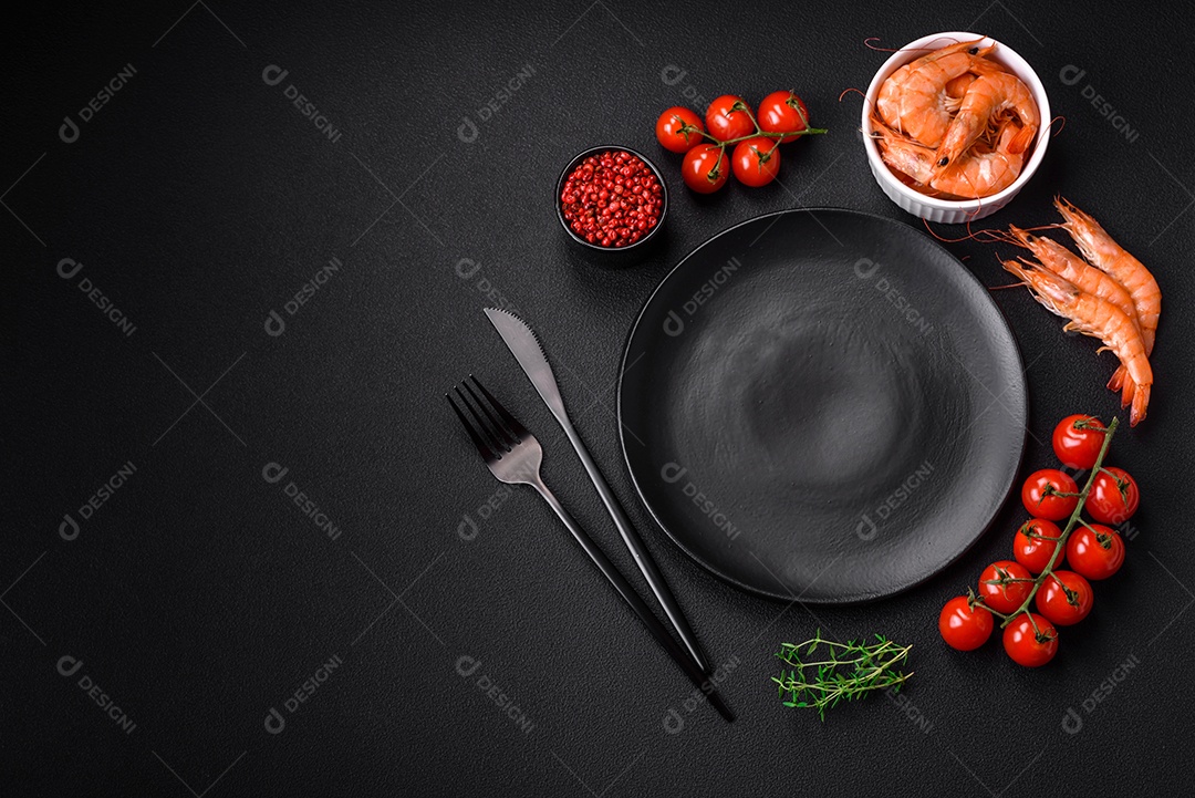 Ingredientes para cozinhar tomate cereja, camarão, sal e especiarias com lugar para inscrição em fundo escuro de concreto