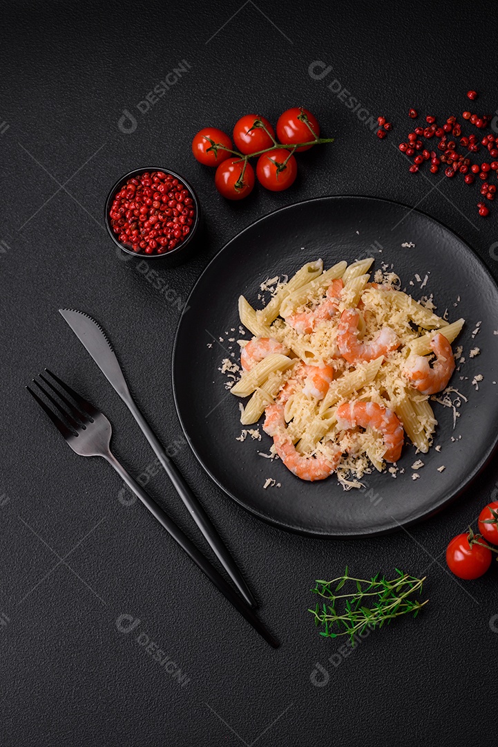Deliciosa massa penna fresca com camarão, molho, queijo, sal e especiarias sobre um fundo escuro de concreto