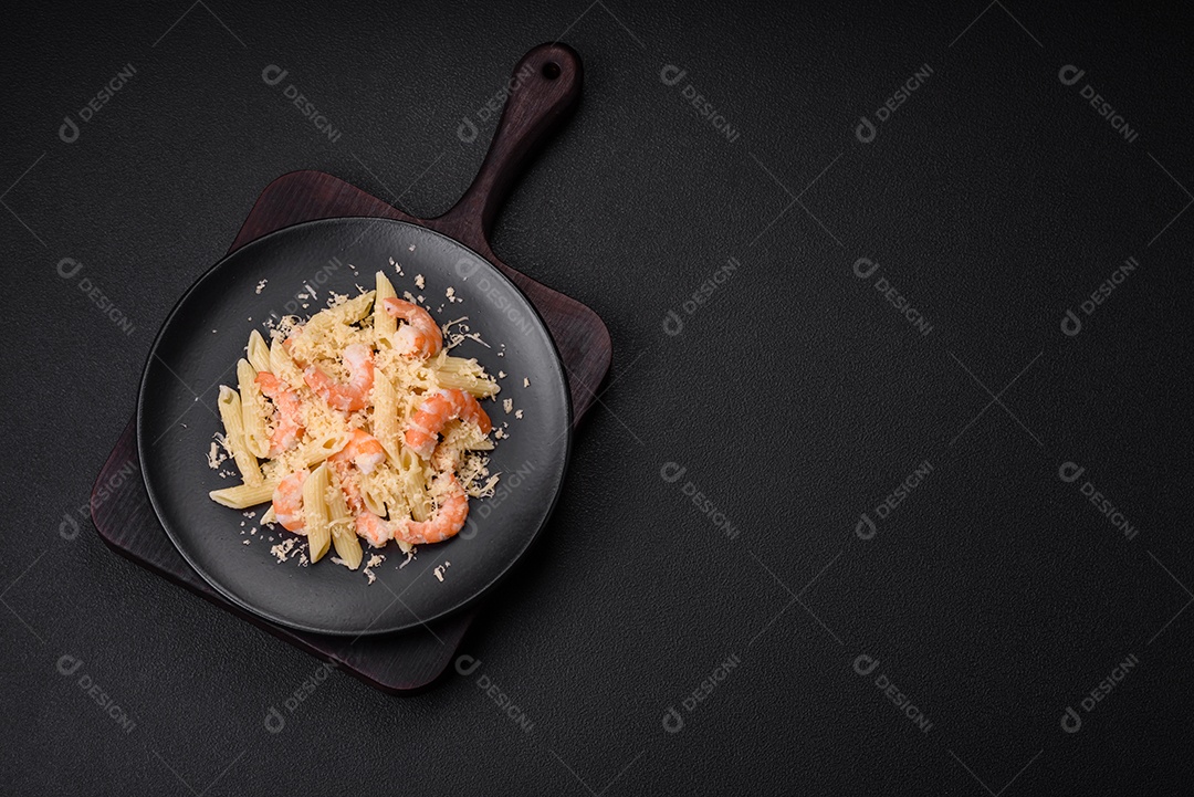 Deliciosa massa penna fresca com camarão, molho, queijo, sal e especiarias sobre um fundo escuro de concreto