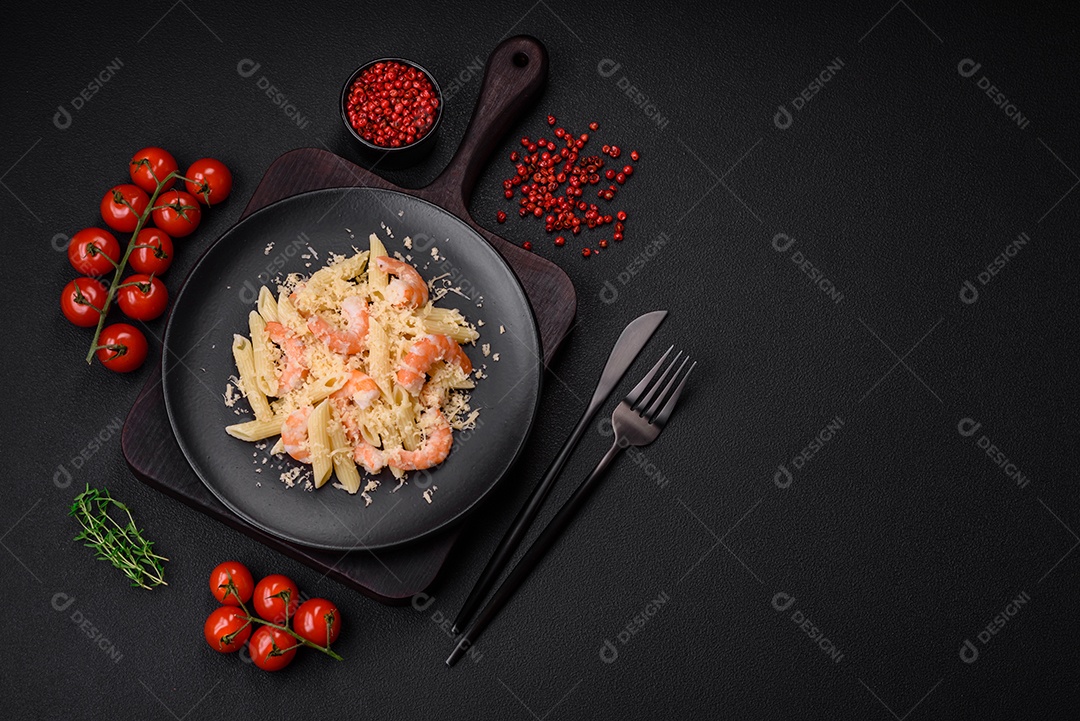 Deliciosa massa penna fresca com camarão, molho, queijo, sal e especiarias sobre um fundo escuro de concreto