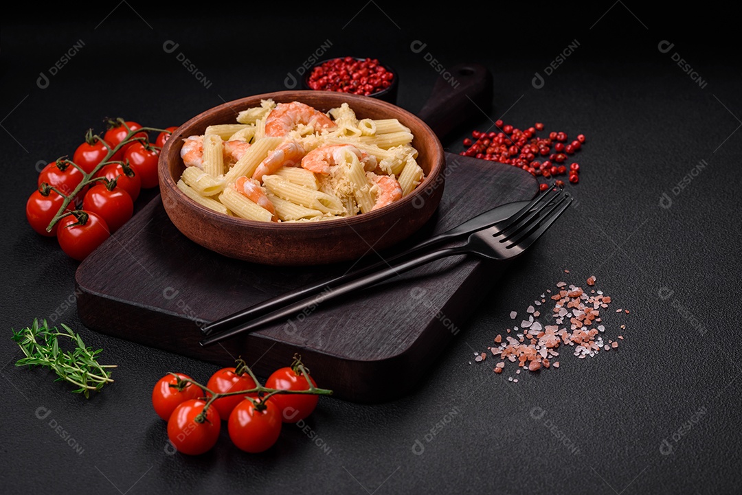 Deliciosa massa penna fresca com camarão, molho, queijo, sal e especiarias sobre um fundo escuro de concreto