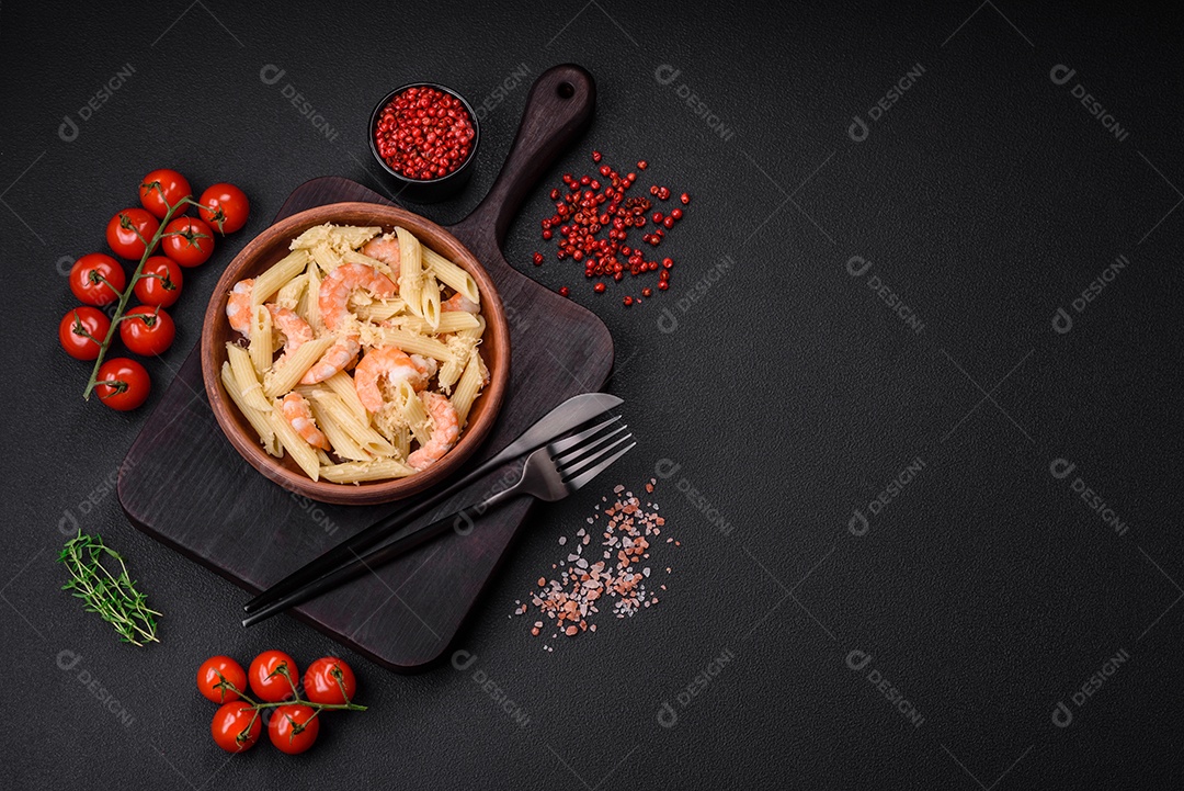 Deliciosa massa penna fresca com camarão, molho, queijo, sal e especiarias sobre um fundo escuro de concreto