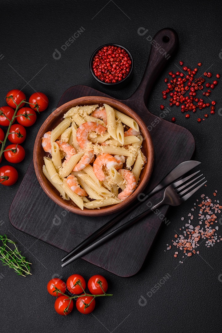 Deliciosa massa penna fresca com camarão, molho, queijo, sal e especiarias sobre um fundo escuro de concreto