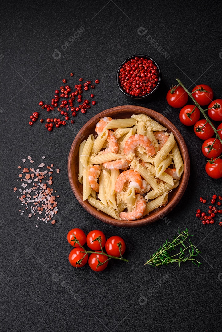 Deliciosa massa penna fresca com camarão, molho, queijo, sal e especiarias sobre um fundo escuro de concreto