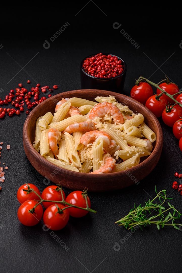 Deliciosa massa penna fresca com camarão, molho, queijo, sal e especiarias sobre um fundo escuro de concreto