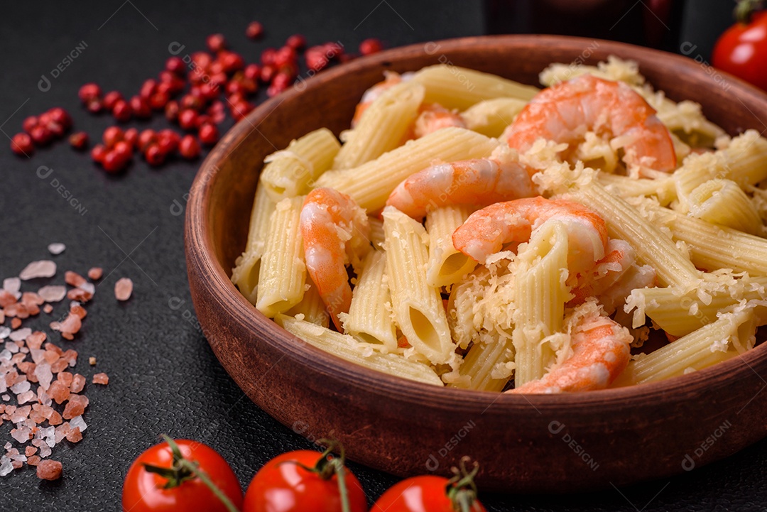 Deliciosa massa penna fresca com camarão, molho, queijo, sal e especiarias sobre um fundo escuro de concreto