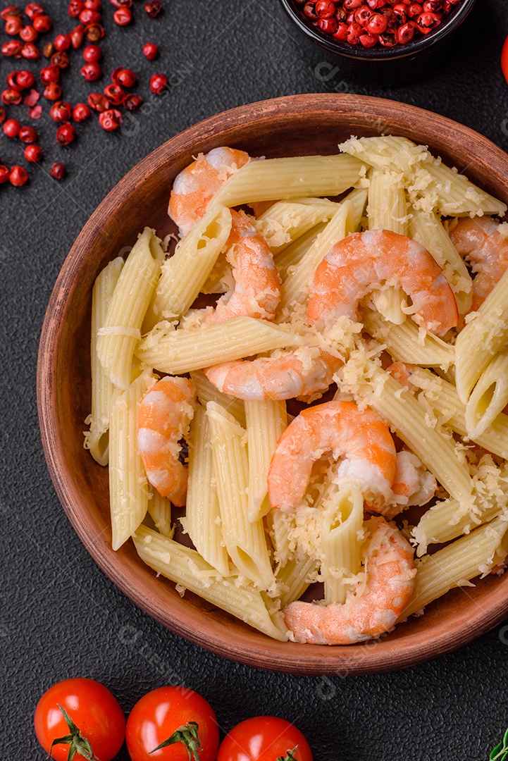 Deliciosa massa penna fresca com camarão, molho, queijo, sal e especiarias sobre um fundo escuro de concreto