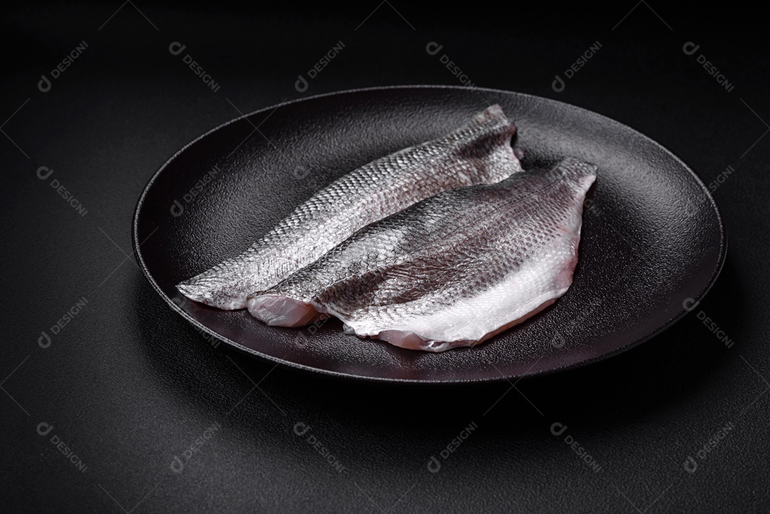 Filé de peixe robalo cru com sal, especiarias e ervas num prato cerâmico preparado para assar