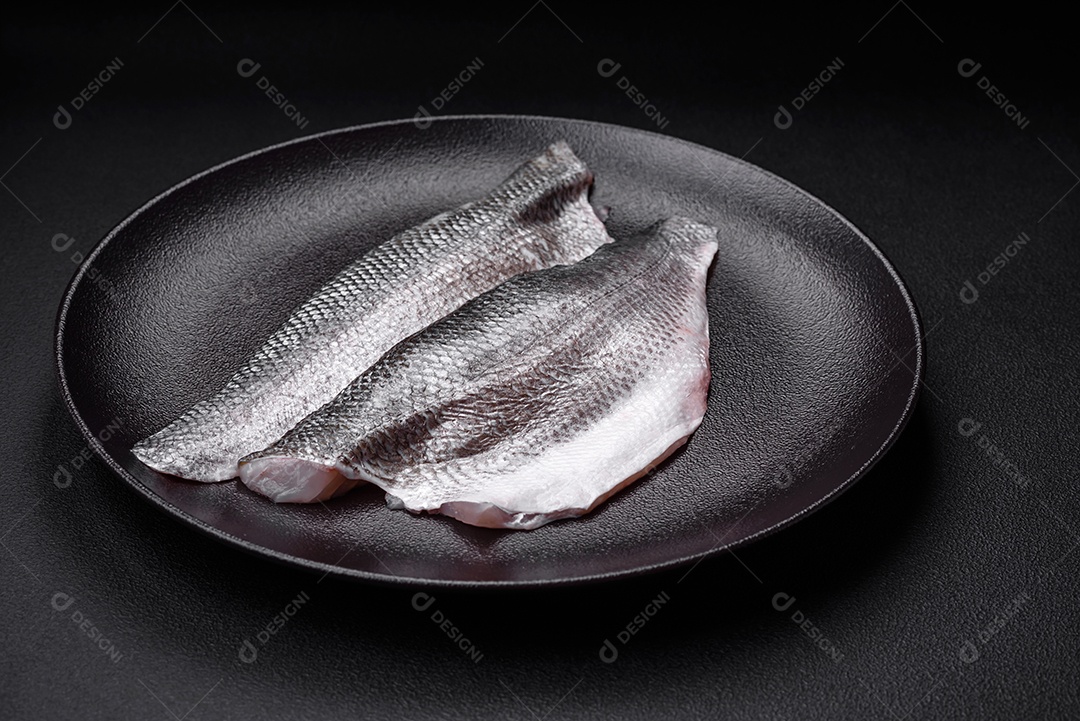 Filé de peixe robalo cru com sal, especiarias e ervas num prato cerâmico preparado para assar