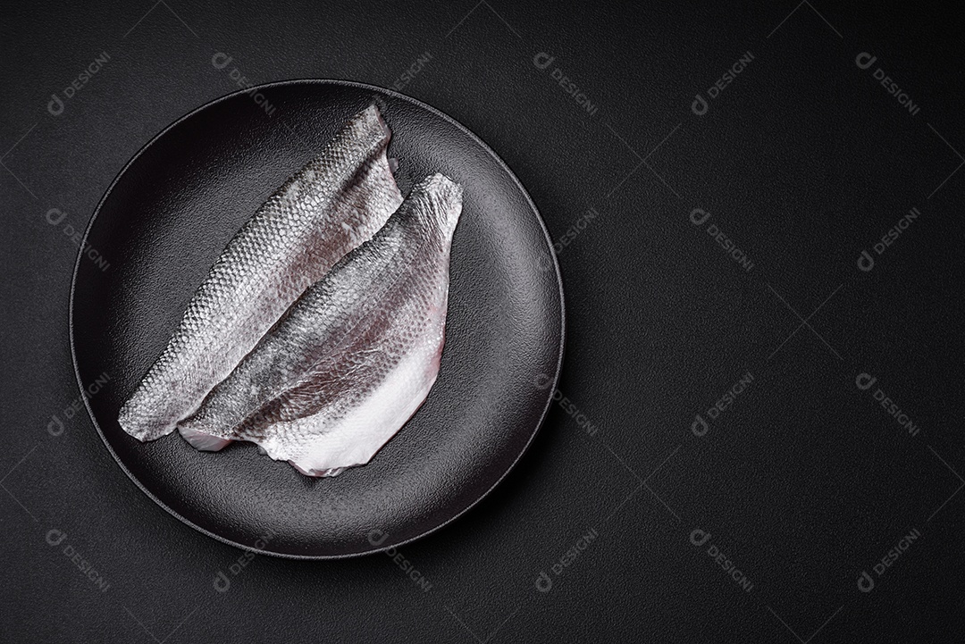 Filé de peixe robalo cru com sal, especiarias e ervas num prato cerâmico preparado para assar