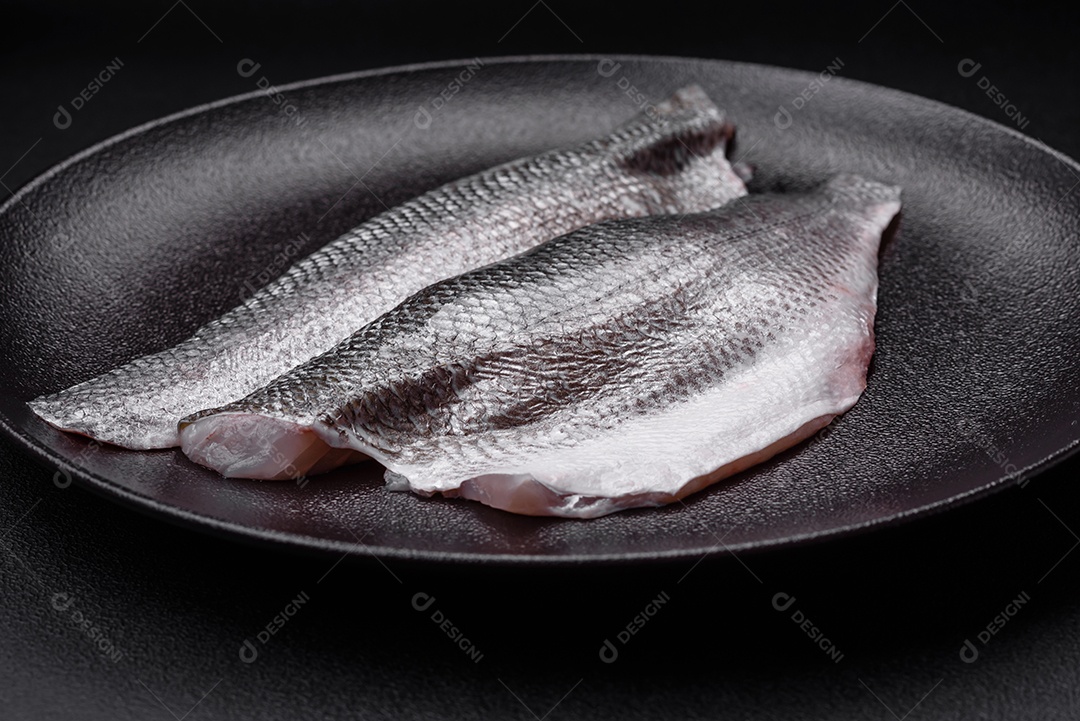 Filé de peixe robalo cru com sal, especiarias e ervas num prato cerâmico preparado para assar