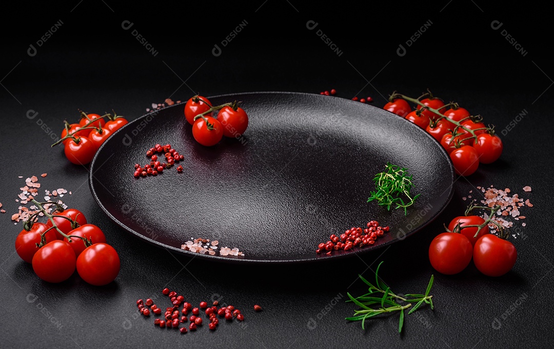 Ingredientes para cozinhar tomate cereja, sal, especiarias e ervas sobre um fundo escuro de concreto