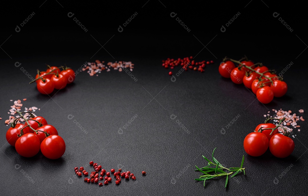 Ingredientes para cozinhar tomate cereja, sal, especiarias e ervas sobre um fundo escuro de concreto
