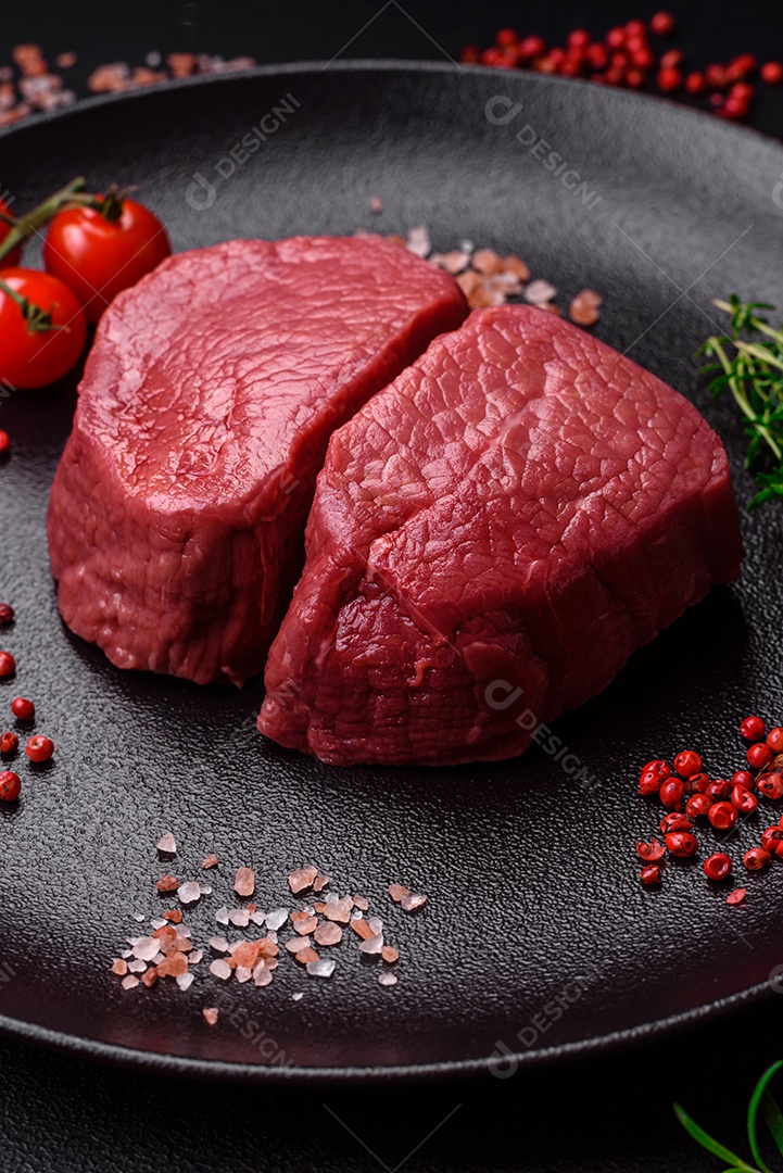 Bife cru redondo com sal, especiarias e ervas preparadas para grelhar em um fundo texturizado