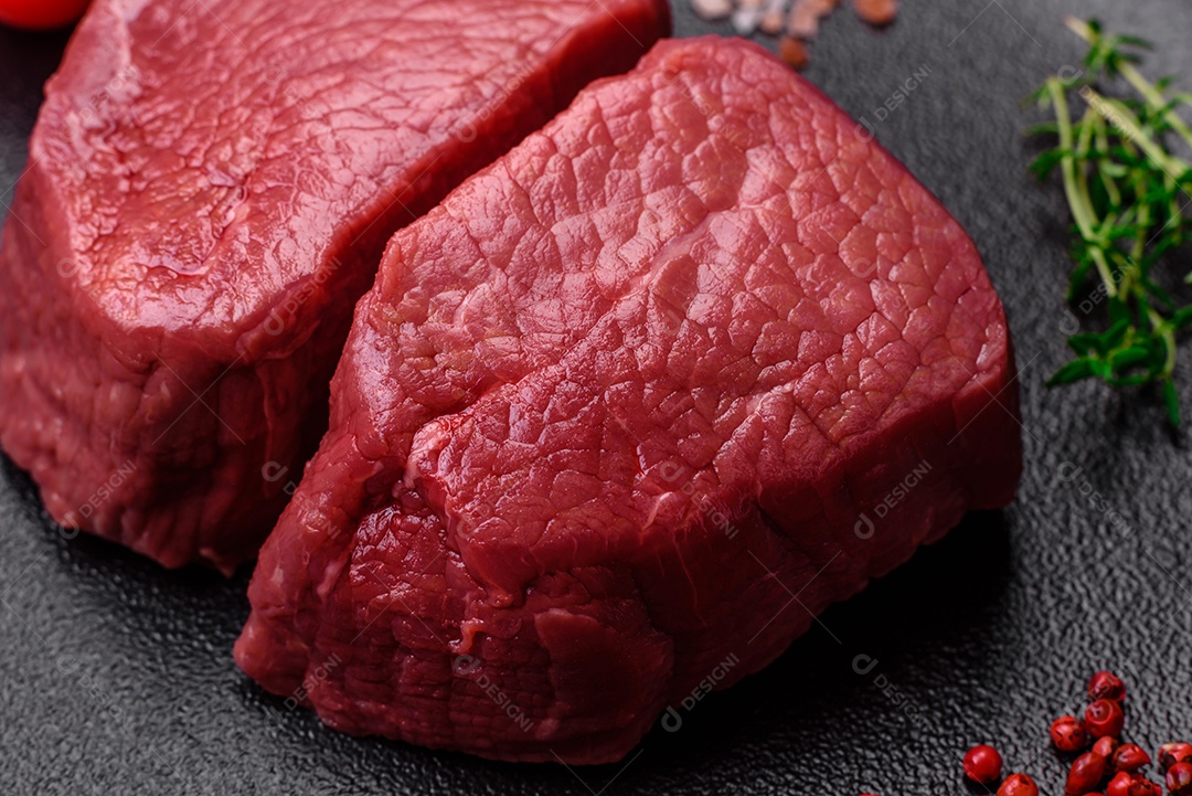 Bife cru redondo com sal, especiarias e ervas preparadas para grelhar em um fundo texturizado