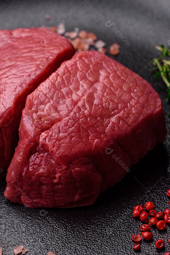 Bife cru redondo com sal, especiarias e ervas preparadas para grelhar em um fundo texturizado