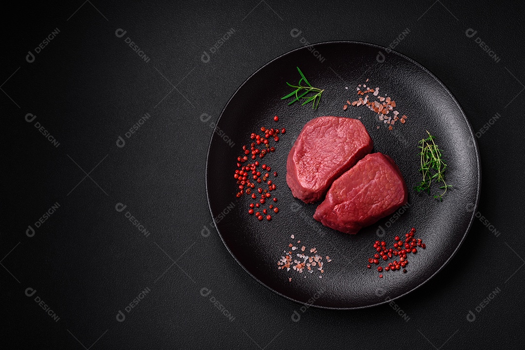 Bife cru redondo com sal, especiarias e ervas preparadas para grelhar em um fundo texturizado