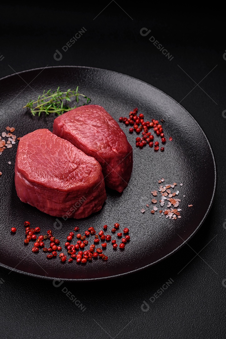 Bife cru redondo com sal, especiarias e ervas preparadas para grelhar em um fundo texturizado