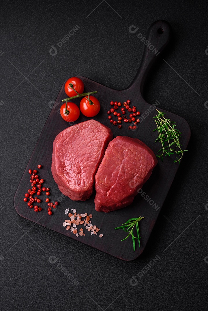 Bife cru redondo com sal, especiarias e ervas preparadas para grelhar em um fundo texturizado