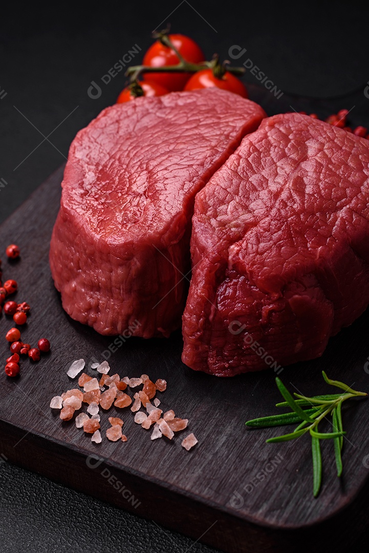 Bife cru redondo com sal, especiarias e ervas preparadas para grelhar em um fundo texturizado