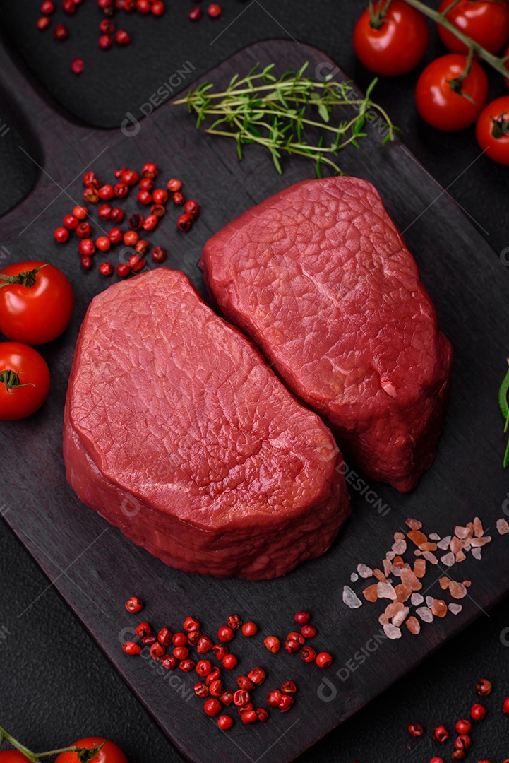 Bife cru redondo com sal, especiarias e ervas preparadas para grelhar em um fundo texturizado