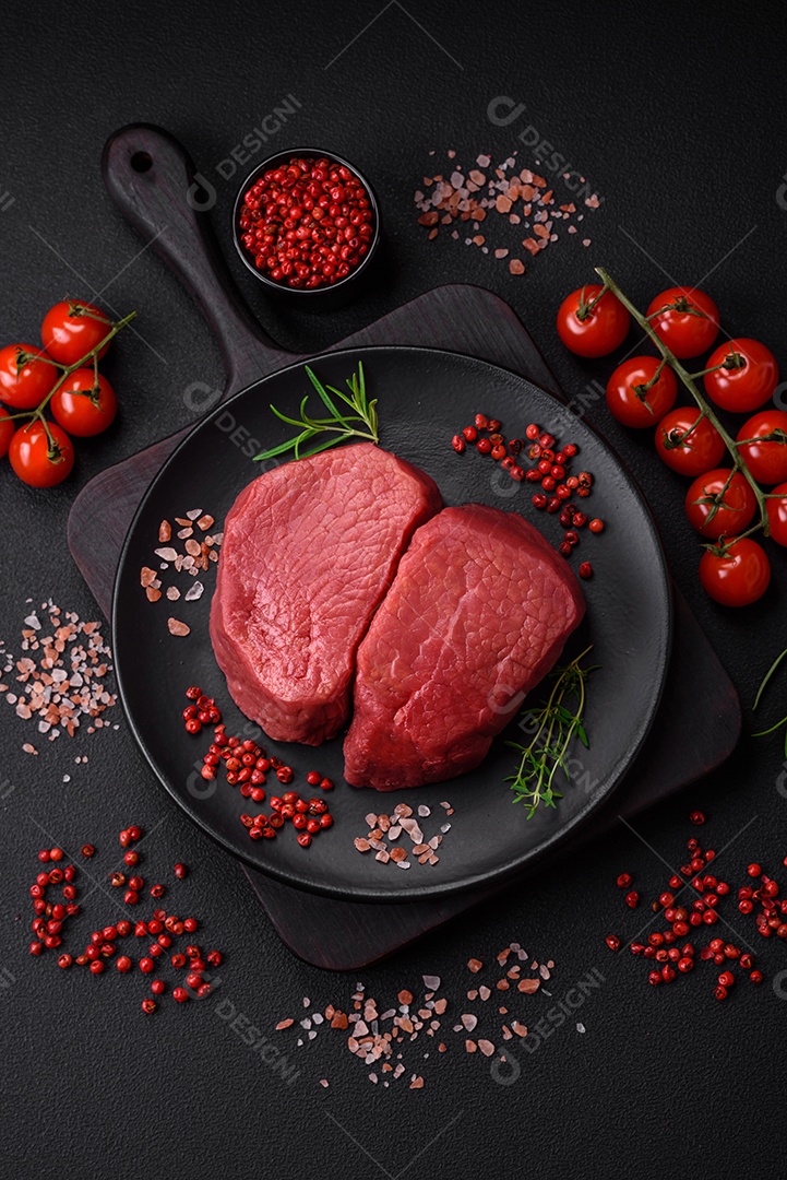 Bife cru redondo com sal, especiarias e ervas preparadas para grelhar em um fundo texturizado