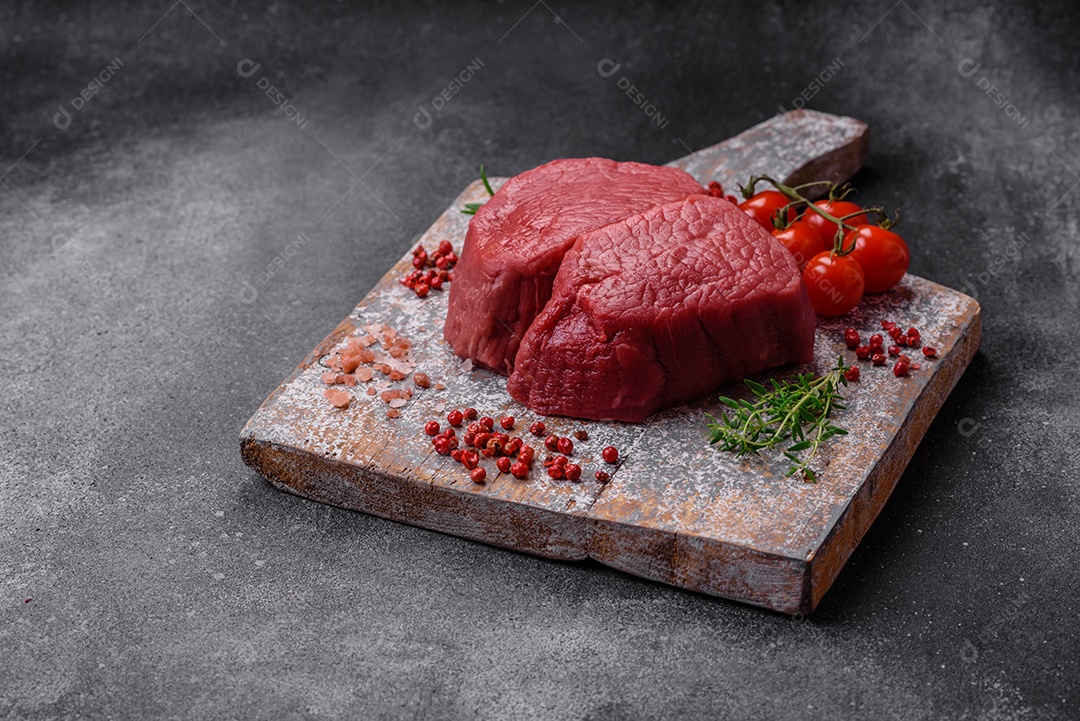 Bife cru redondo com sal, especiarias e ervas preparadas para grelhar em um fundo texturizado