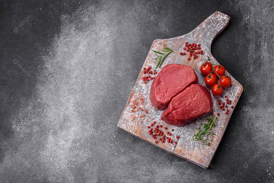 Bife cru redondo com sal, especiarias e ervas preparadas para grelhar em um fundo texturizado