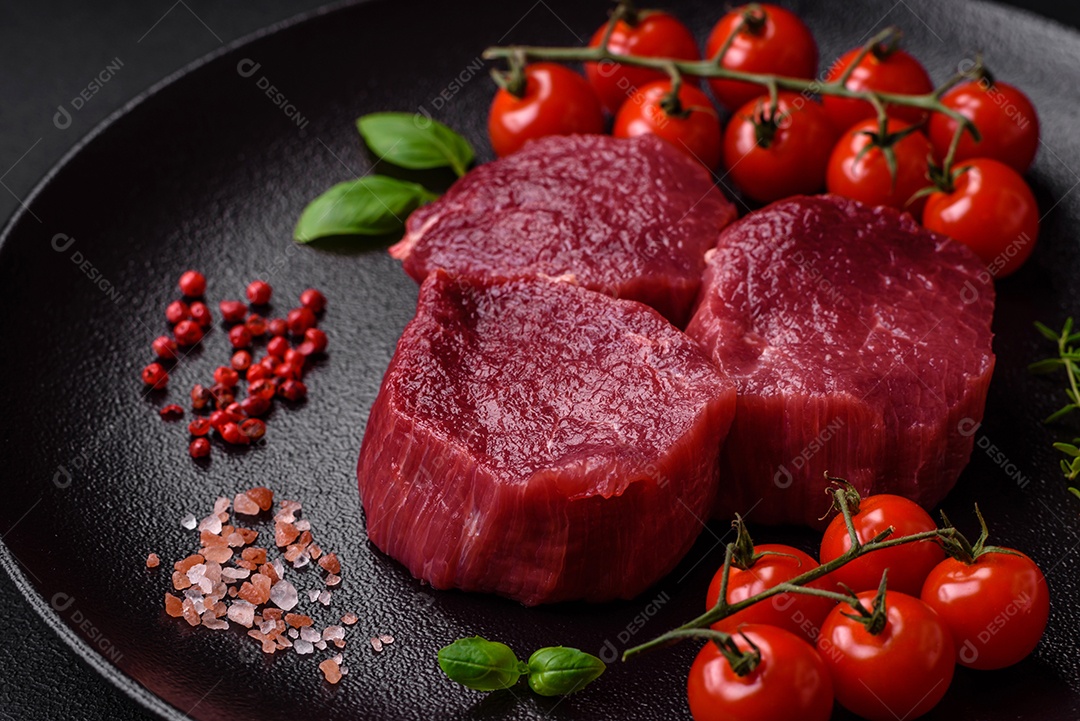 Carne crua suculenta com especiarias, sal e ervas sobre um fundo escuro de concreto. Preparando-se para cozinhar um prato de carne