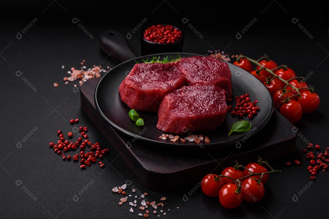 Carne crua suculenta com especiarias, sal e ervas sobre um fundo escuro de concreto. Preparando-se para cozinhar um prato de carne