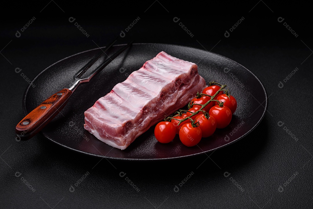 Costelas de porco cruas com sal, especiarias e ervas em fundo de concreto texturizado