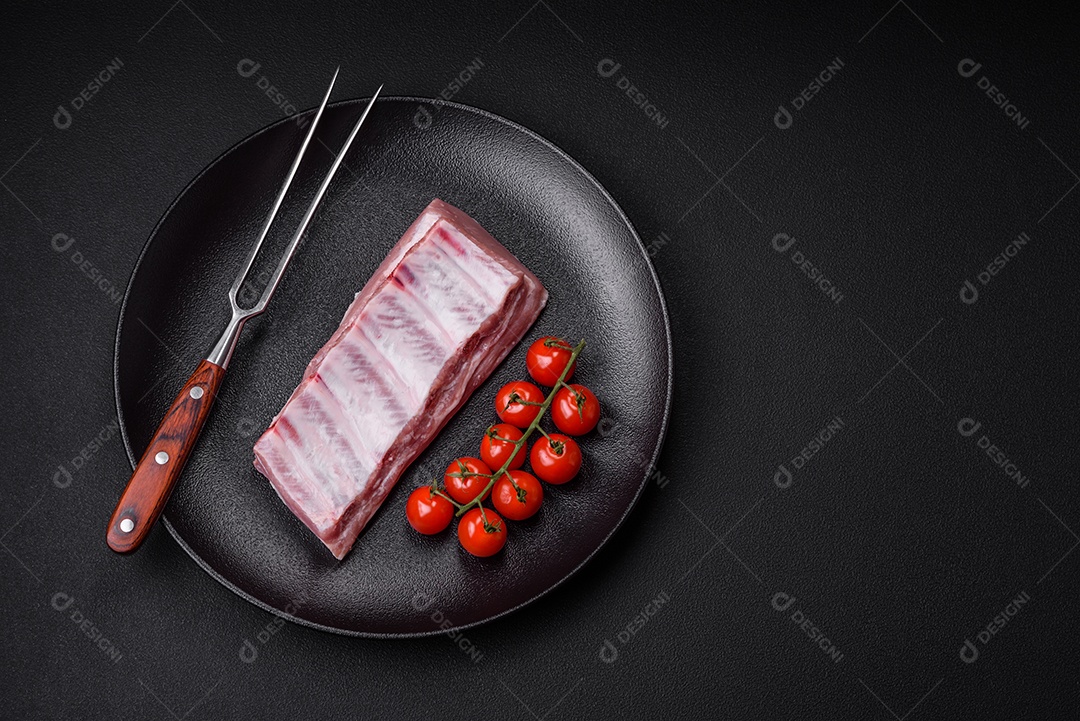 Costelas de porco cruas com sal, especiarias e ervas em fundo de concreto texturizado