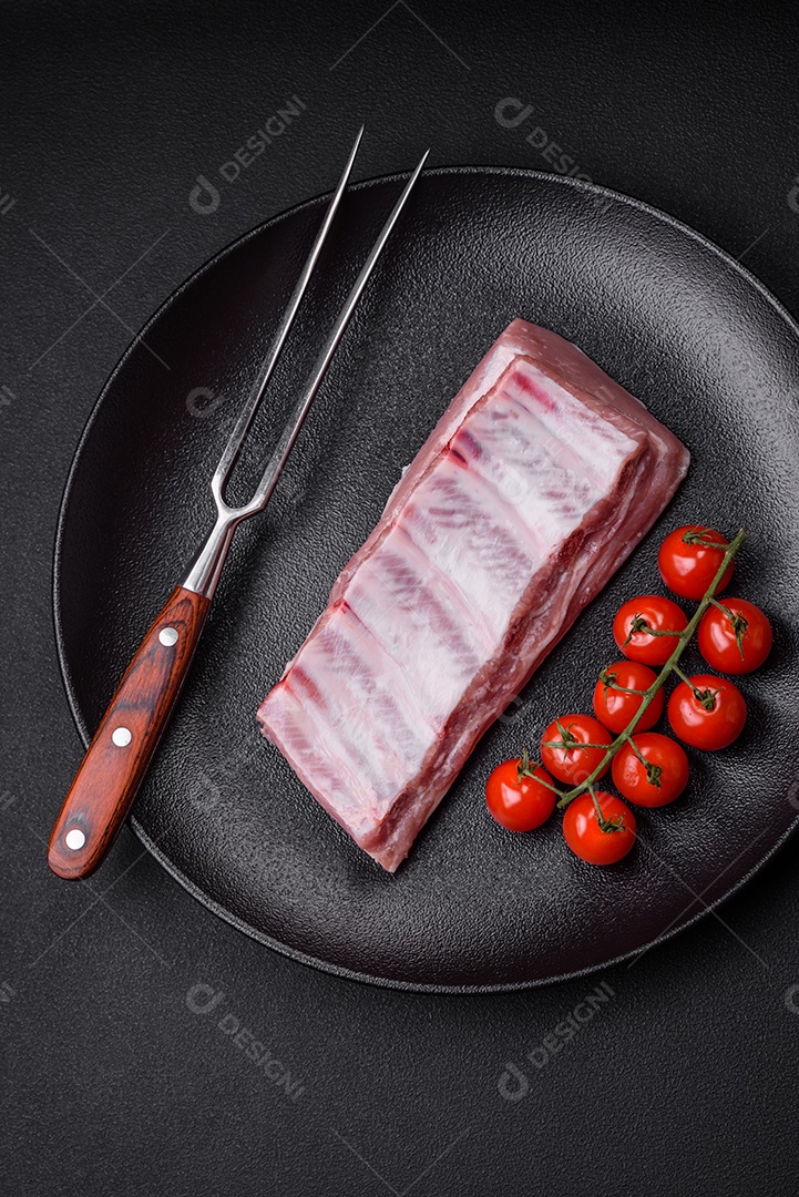 Costelas de porco cruas com sal, especiarias e ervas em fundo de concreto texturizado