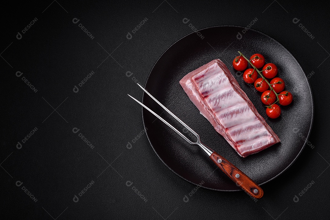 Costelas de porco cruas com sal, especiarias e ervas em fundo de concreto texturizado