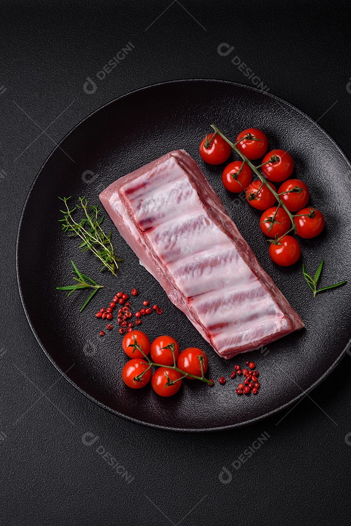 Costelas de porco cruas com sal, especiarias e ervas em fundo de concreto texturizado