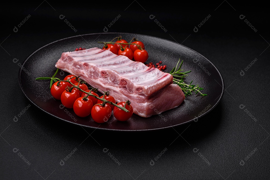 Costelas de porco cruas com sal, especiarias e ervas em fundo de concreto texturizado