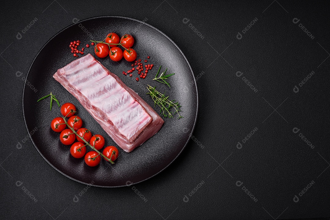 Costelas de porco cruas com sal, especiarias e ervas em fundo de concreto texturizado