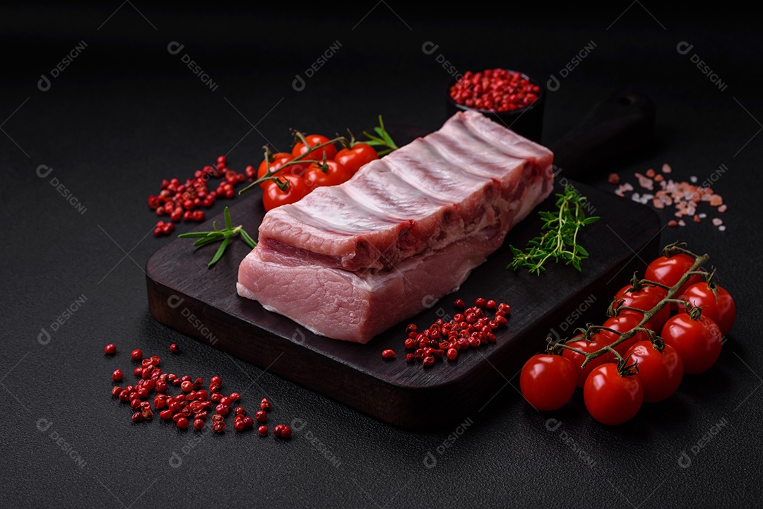 Costelas de porco cruas com sal, especiarias e ervas em fundo de concreto texturizado